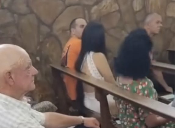 No vídeo gravado por uma pessoa que estava no local mostra o homem abraçado com a mulher, enquanto prestam atenção na missa.(Foto: reprodução vídeo)