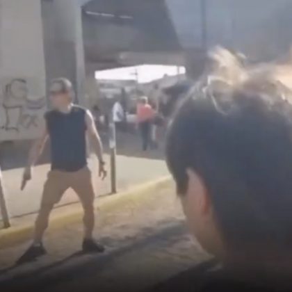 Enquanto isso, um outro homem saca uma arma, aponta para o garoto e discute com uma moça que gravava a cena na rua. (Foto: reprodução vídeo)