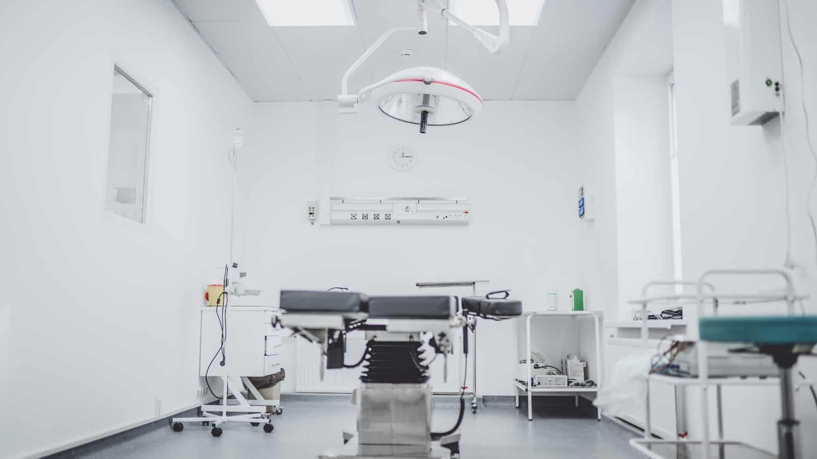 An operating room with a surgical table, overhead light, and medical equipment