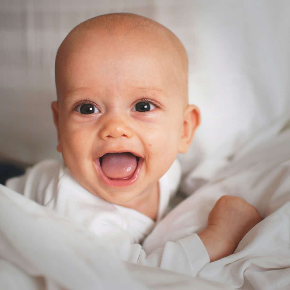 baby smiling on white cushion