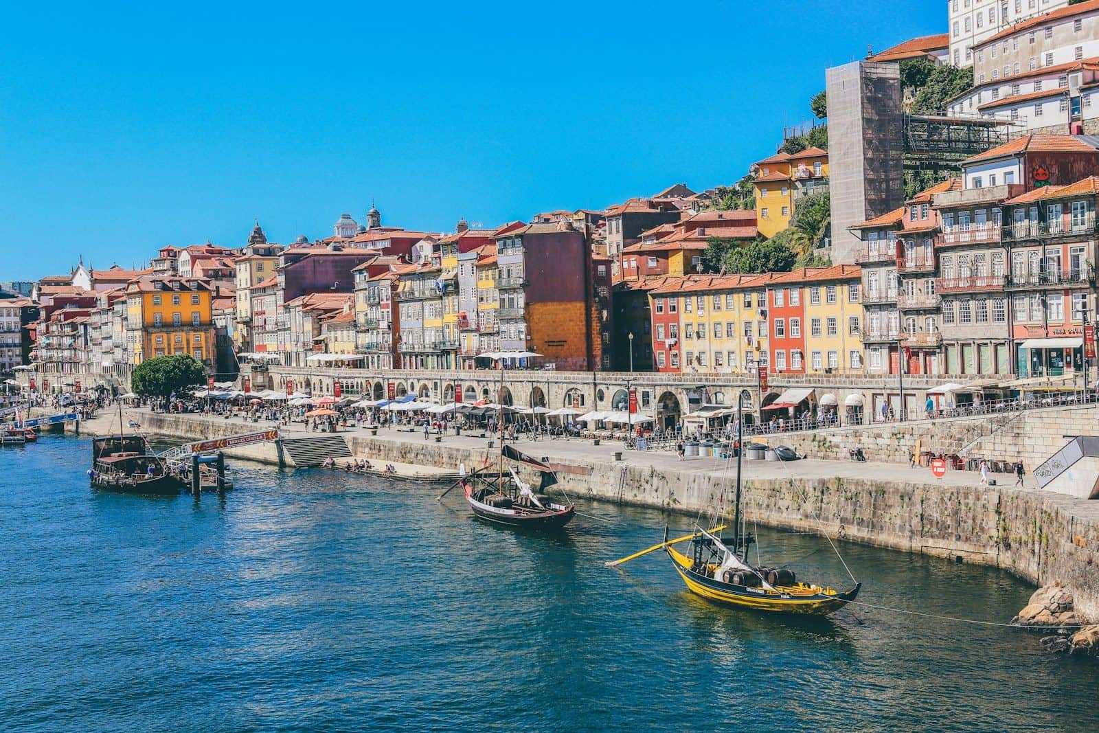 Traditional wooden boats on the Douro River in Porto, Portugal, with colorful buildings.