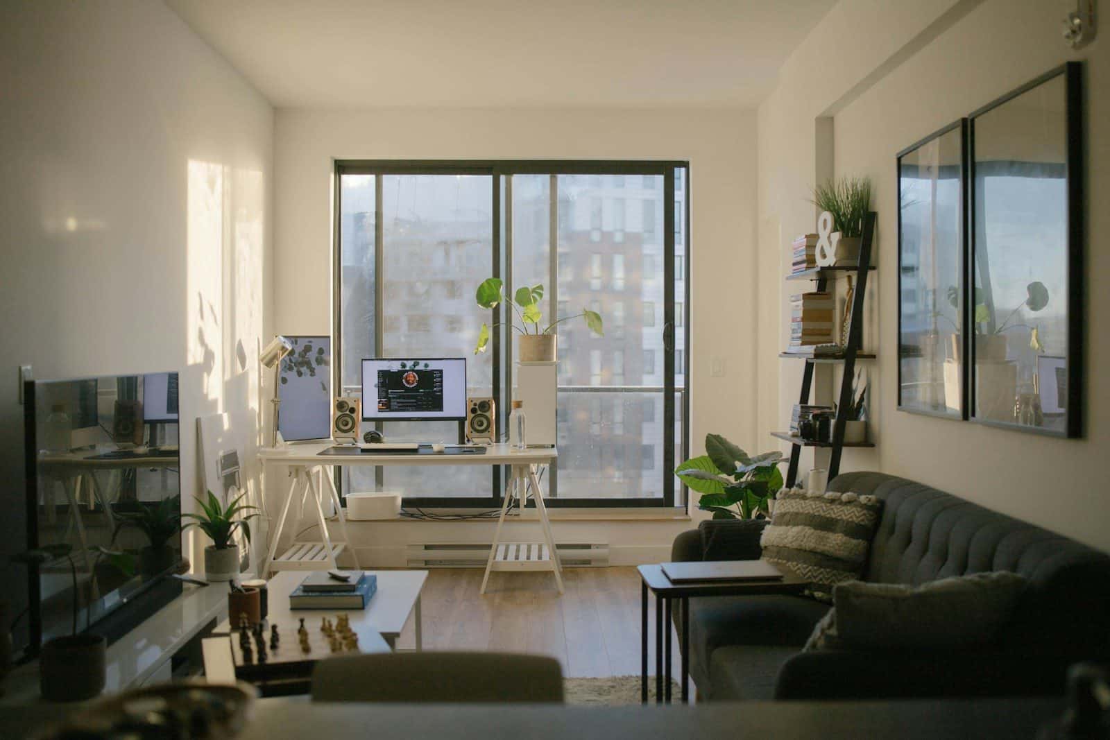 A sunlit home office with a desk, computer, and sofa in a living room