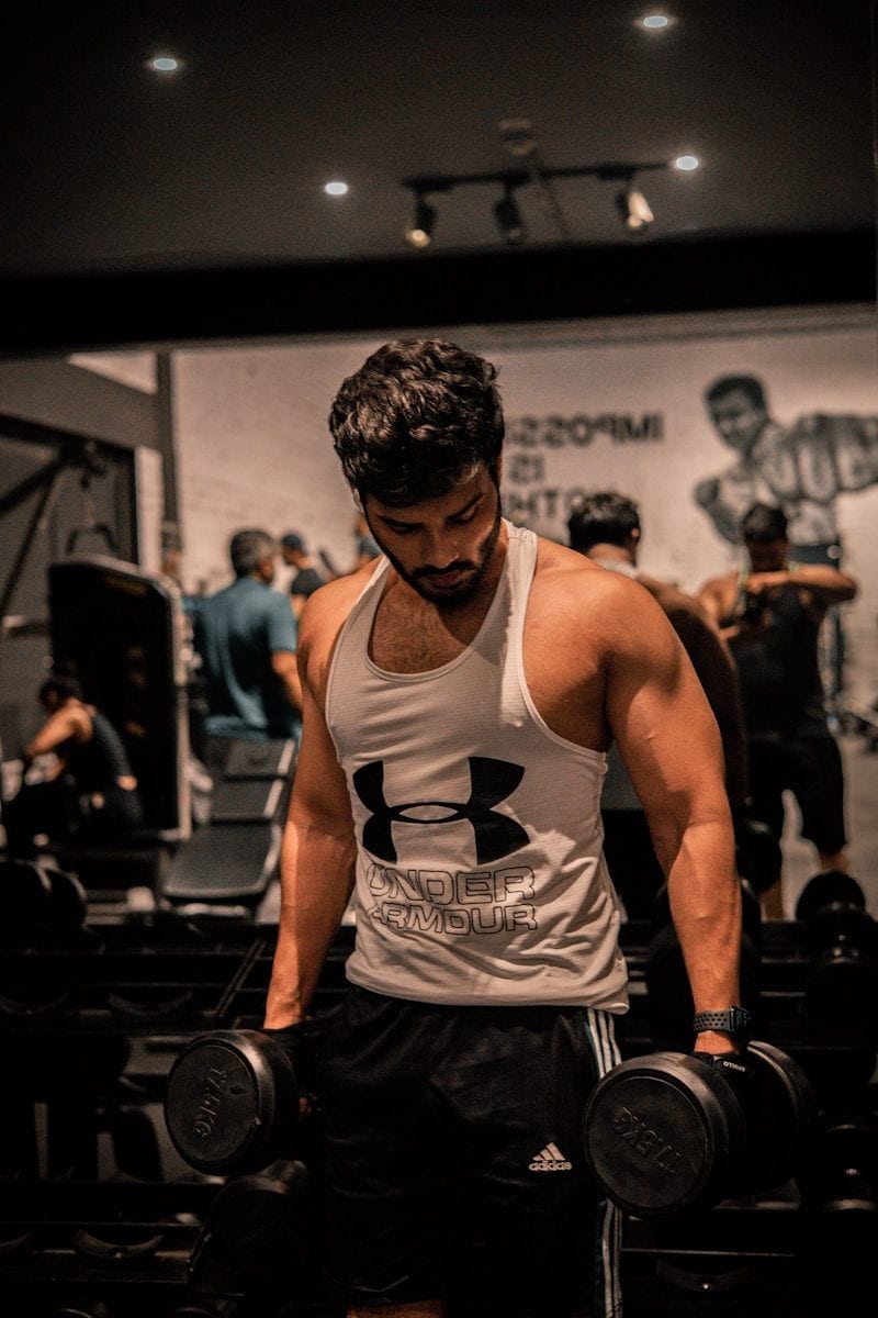 A muscular man lifts dumbbells at the gym