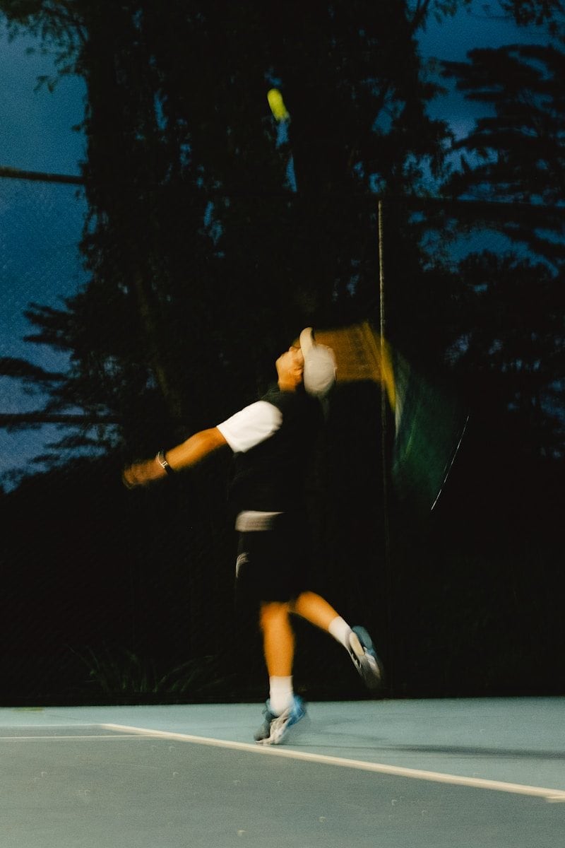 A tennis player hitting a ball at night