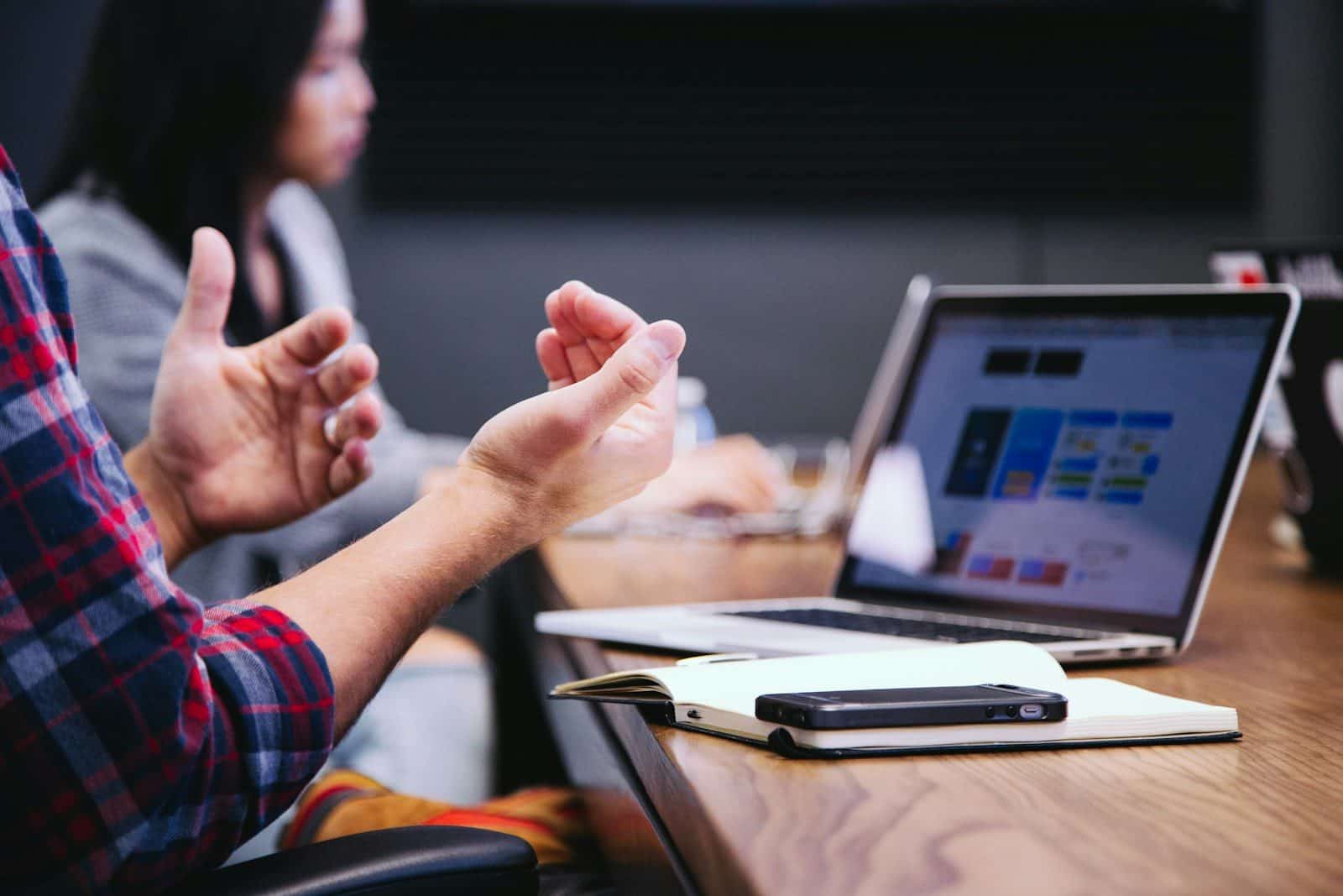 person gesturing during meeting with laptop