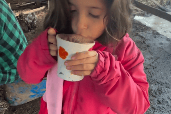 Mãe mostra como a filha toma seu leite com achocolatado antes de ir para a escola na roça