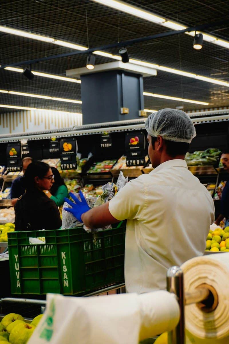 Worker stocking produce in a supermarket aisle