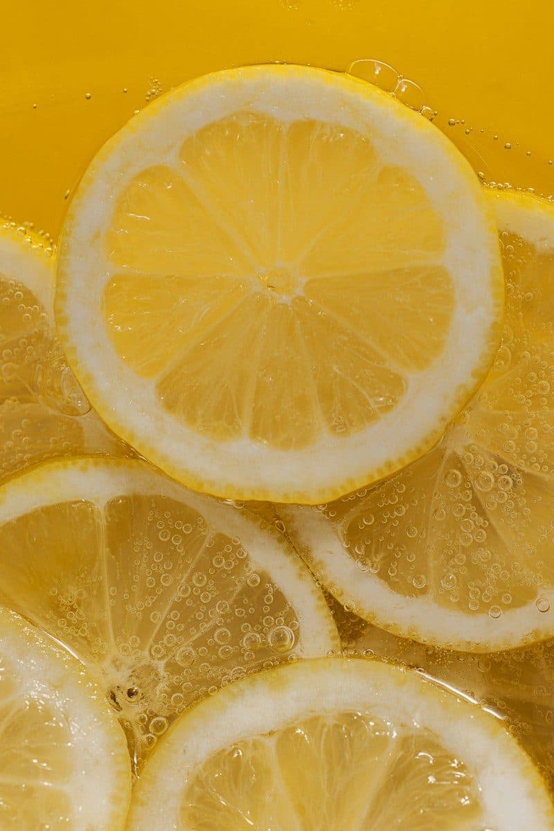 Lemon slices submerged in a carbonated yellow liquid with small air bubbles