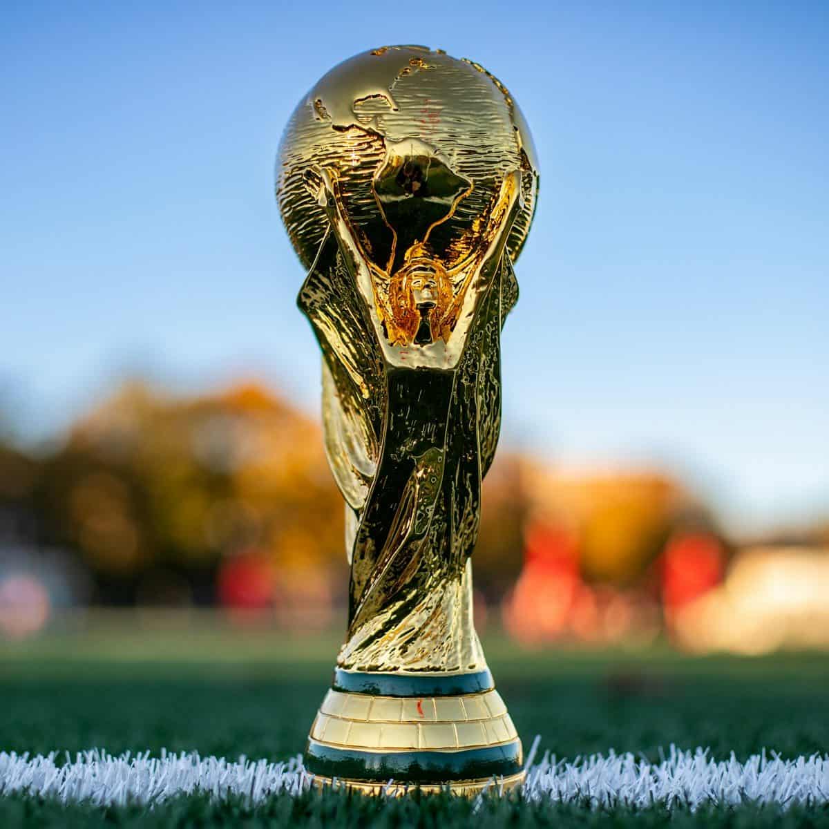 A gold trophy featuring two figures holding up a globe on a green field