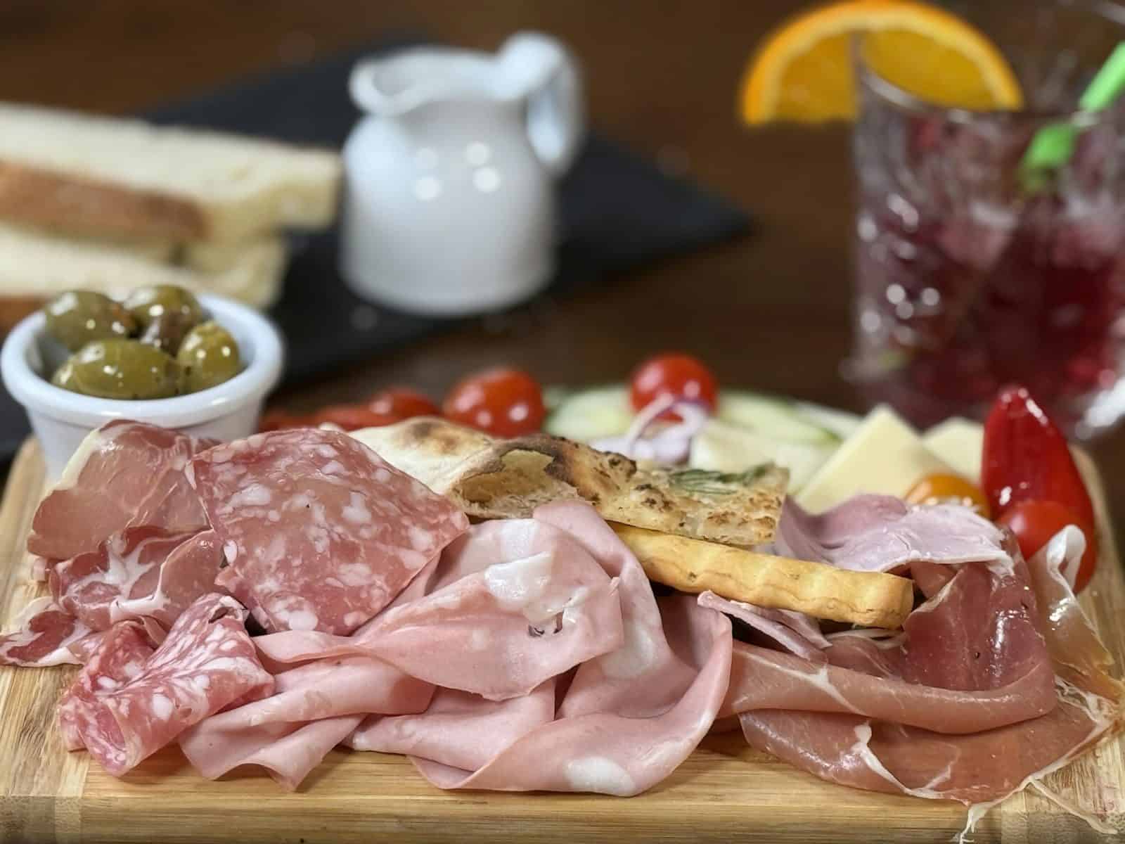 Charcuterie board with meats, cheese, olives, and bread