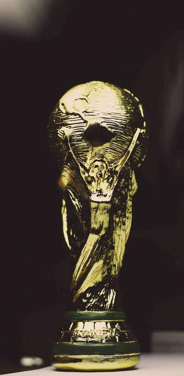 A gold trophy featuring a globe supported by figures on a dark background