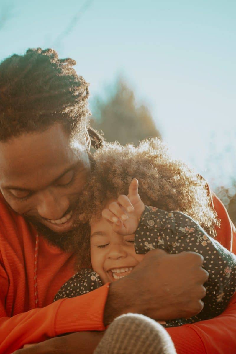 father hugging laughing young daughter