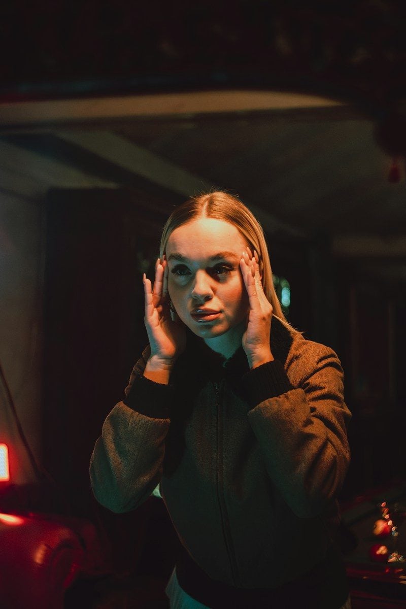 Young woman with hands on temples in dim lighting