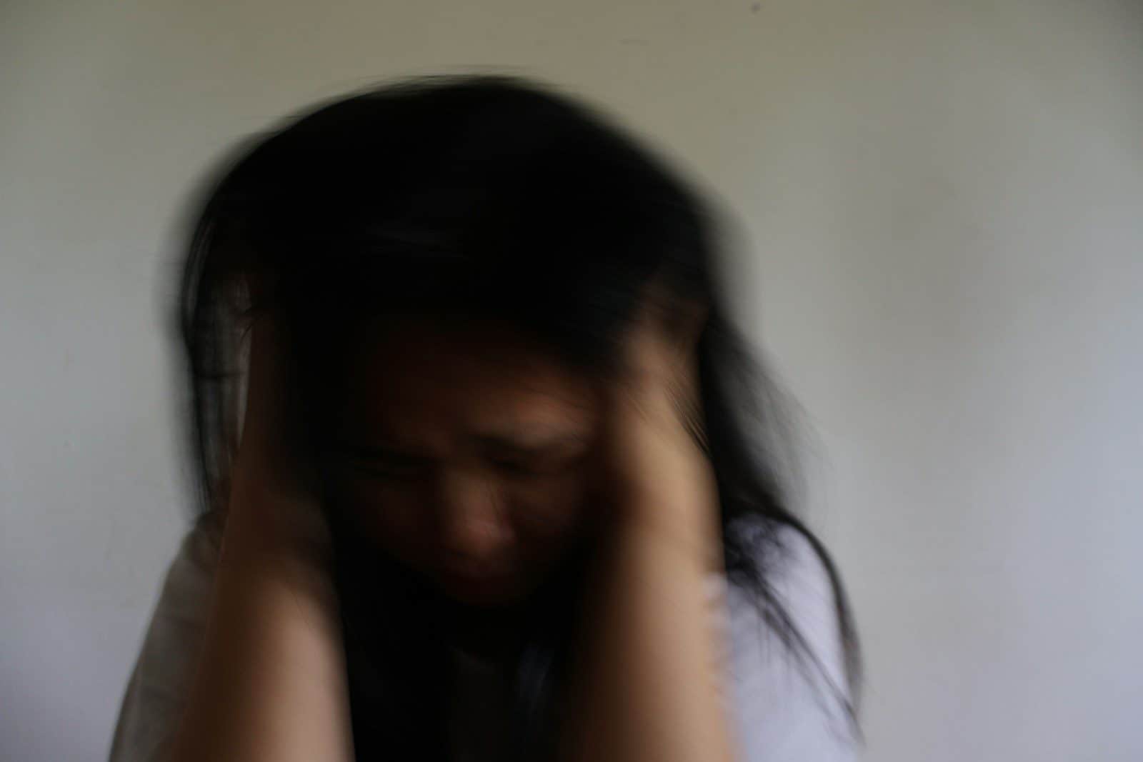 A blurred woman holding her head