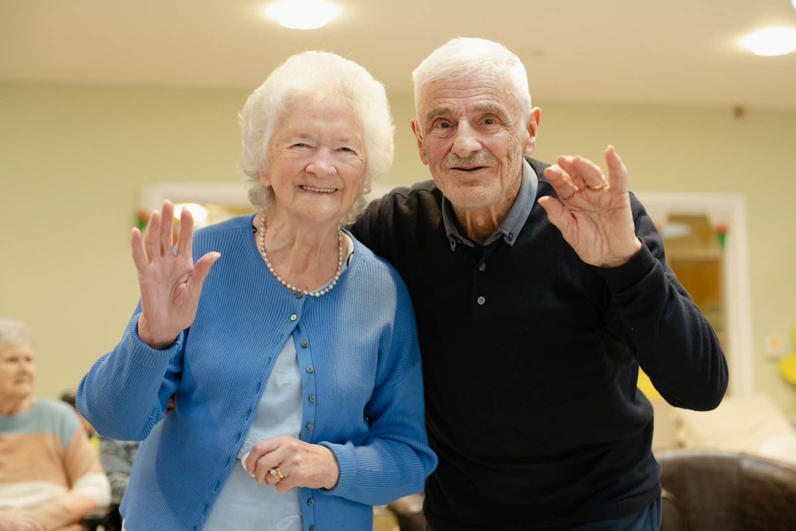 Elderly couple waving and smiling at the camera