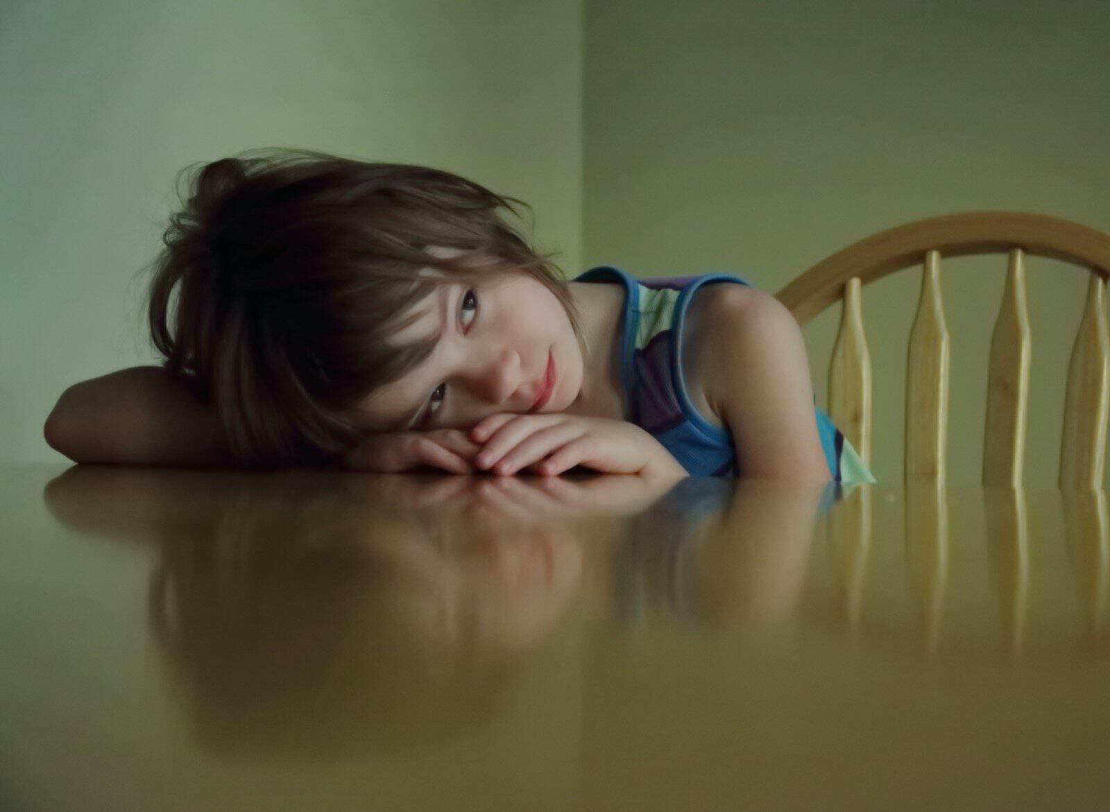 A young child rests their head on a table
