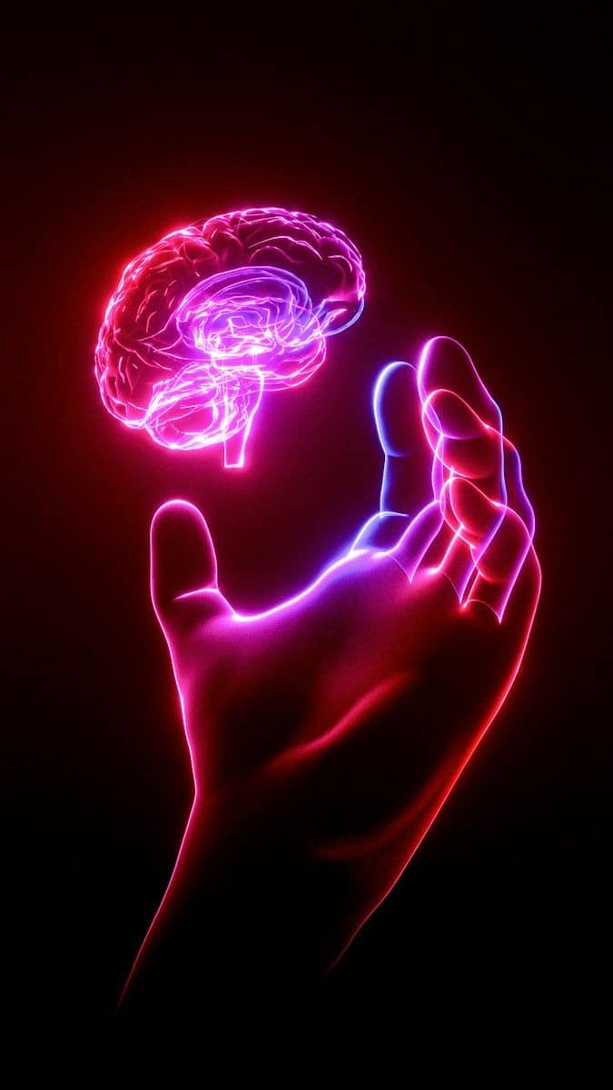 A person's hand holding a glowing brain model