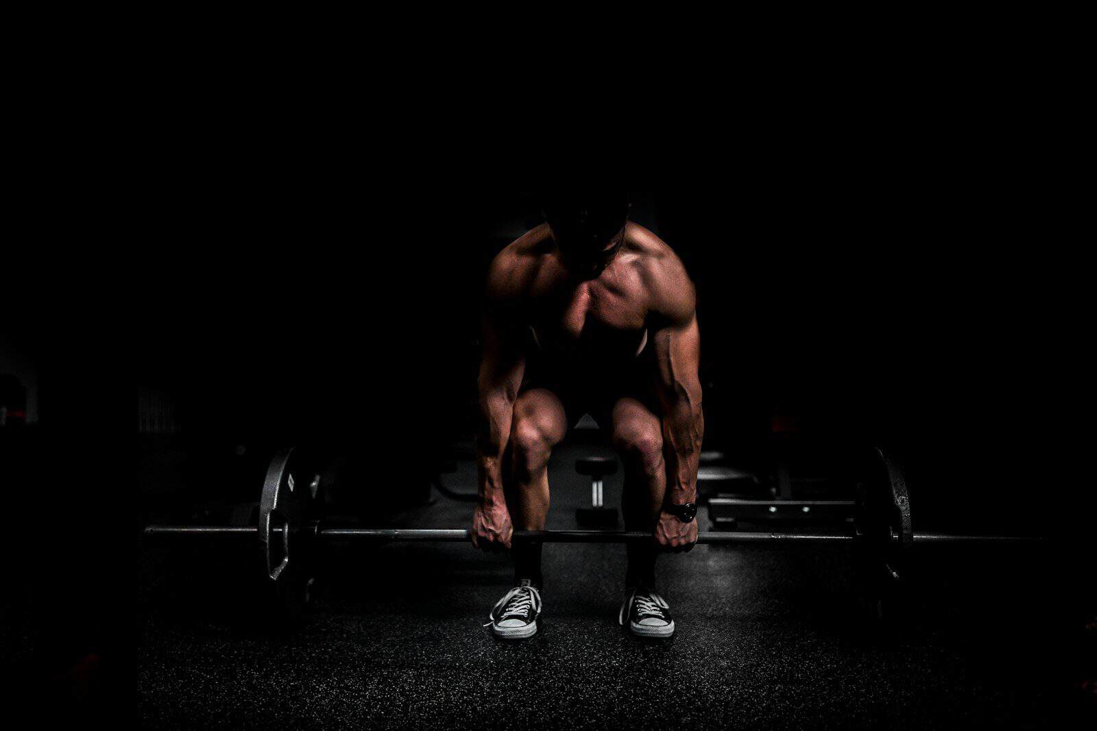 shirtless man lifting barbell in gym