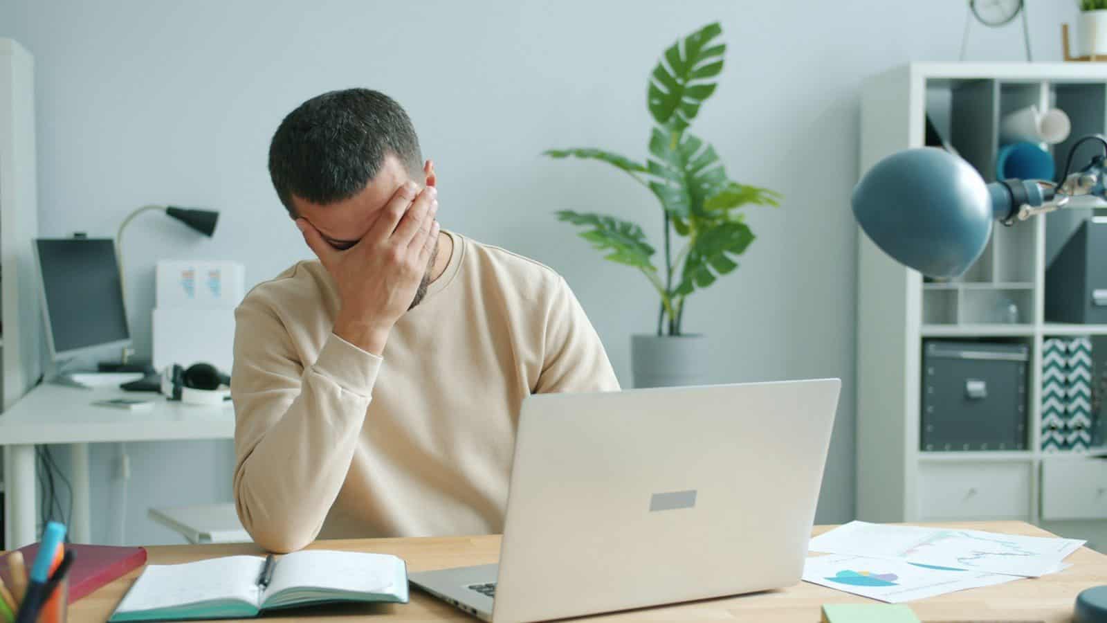 Man rubbing his face in front of laptop