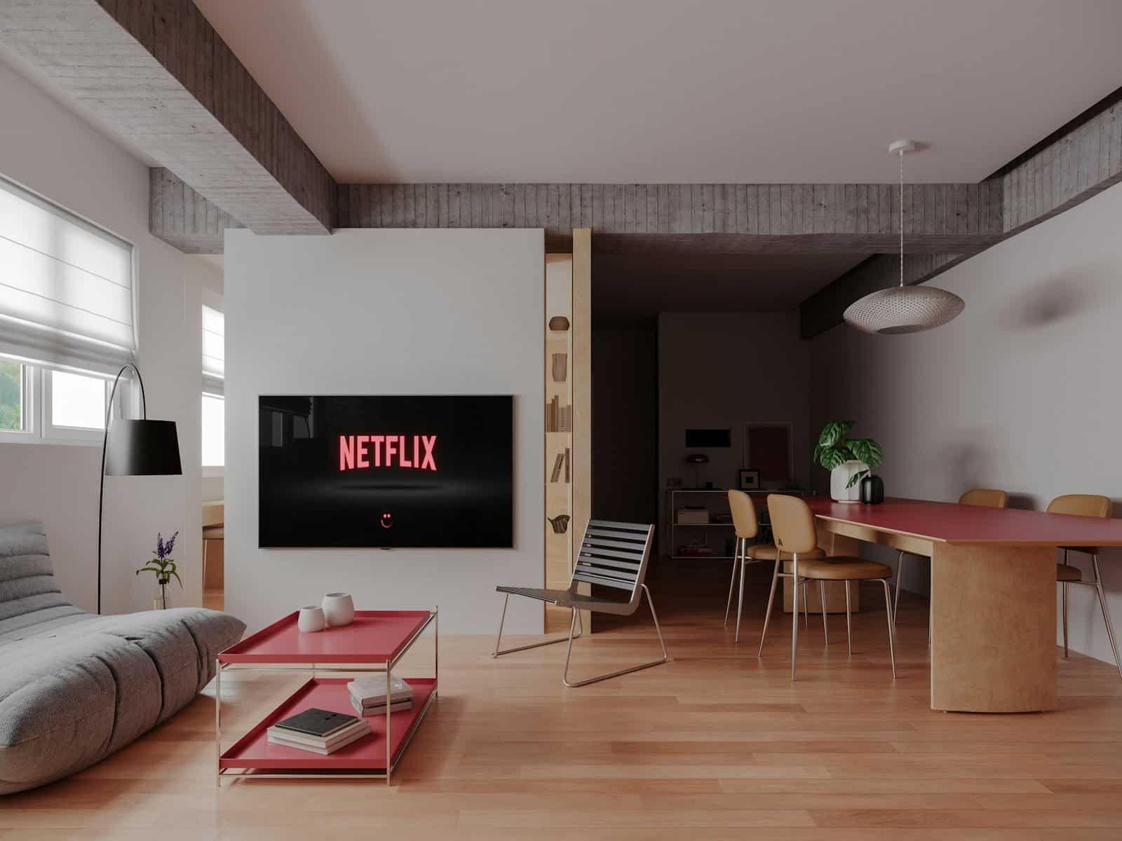 A modern living room with a television displaying a logo, red table, and chairs