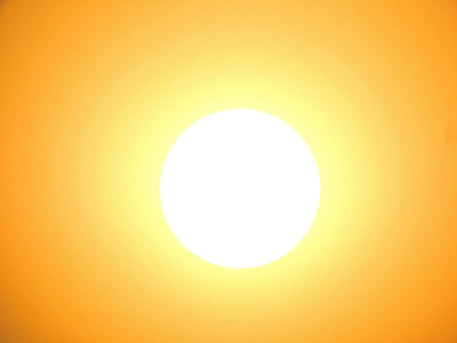 A bright white sun centered against a vibrant orange sky