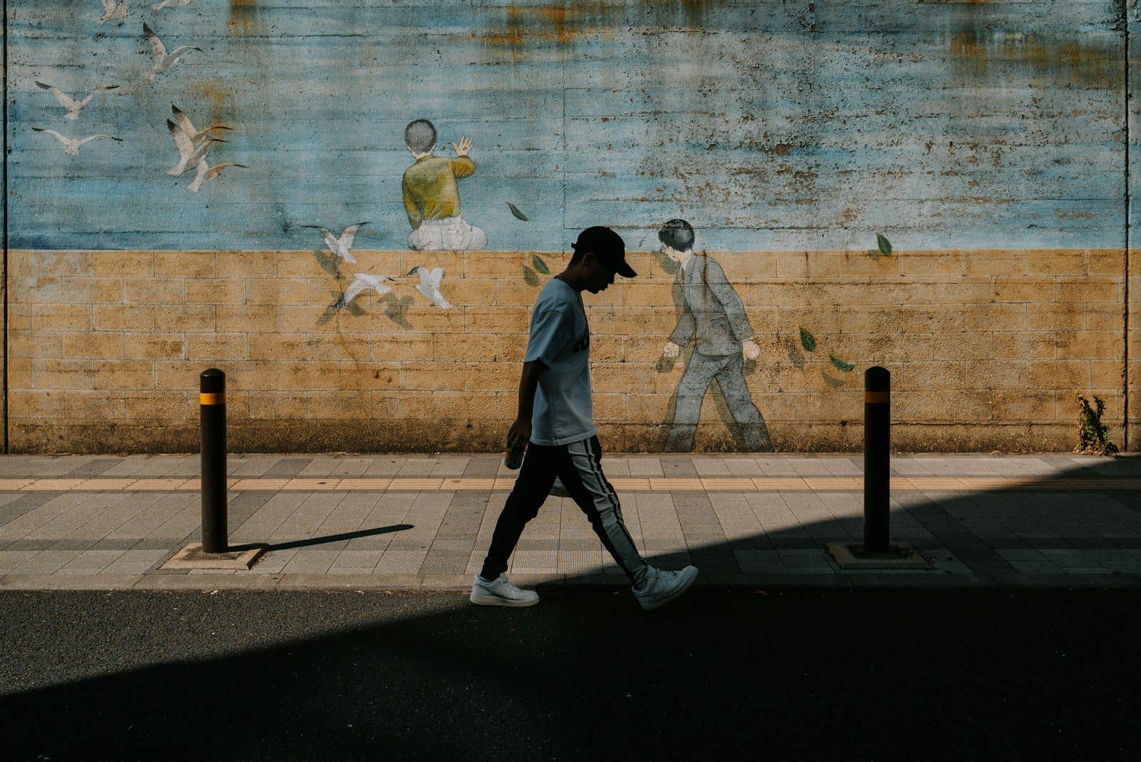 Man walks past mural on a sunny day