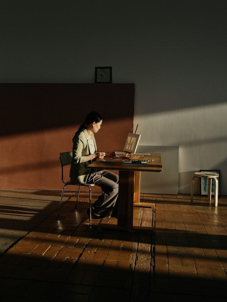 Woman painting at a wooden table in sunlight