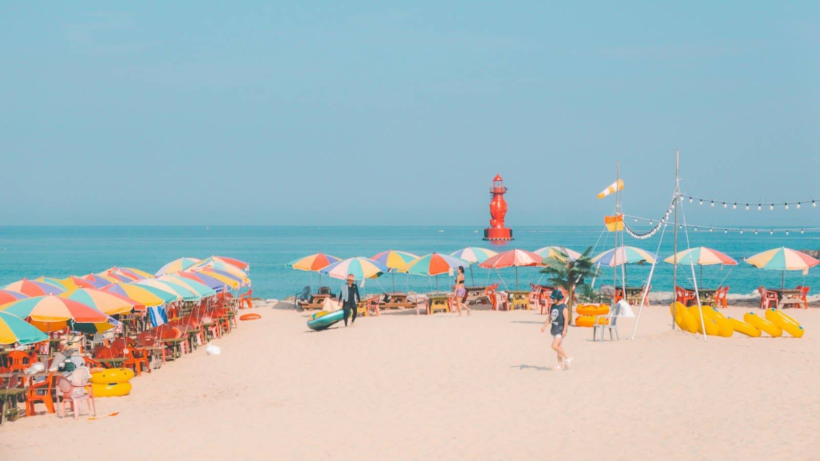 Colorful umbrellas line a sunny beach with ocean background