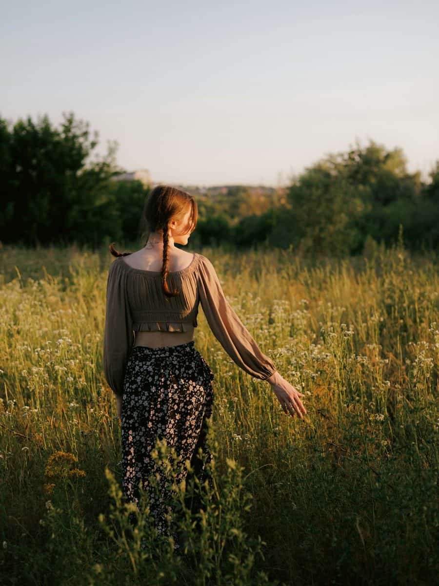 Young woman with braids walks through a sunlit field