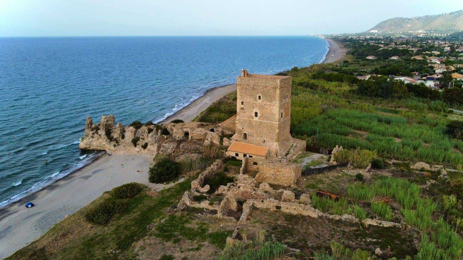 A coastal castle tower stands overlooking the sea